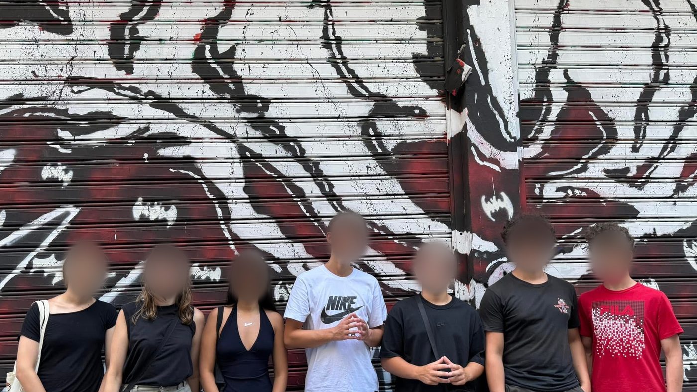 Estudantes diante de um muro grafitado em Atenas