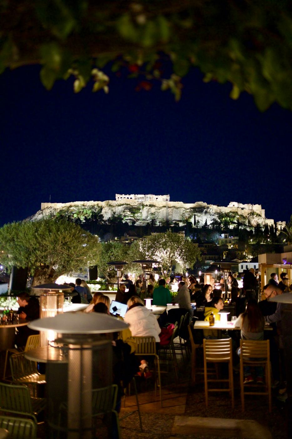 Um restaurante num terraço à noite, sob a Acrópole iluminada, em Atenas