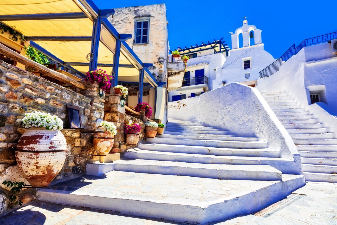 Escadas caiadas, flores e uma capela de cúpula azul numa aldeia de Naxos